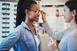 Optique Jeune femme qui essaie des lunettes avec un opticien